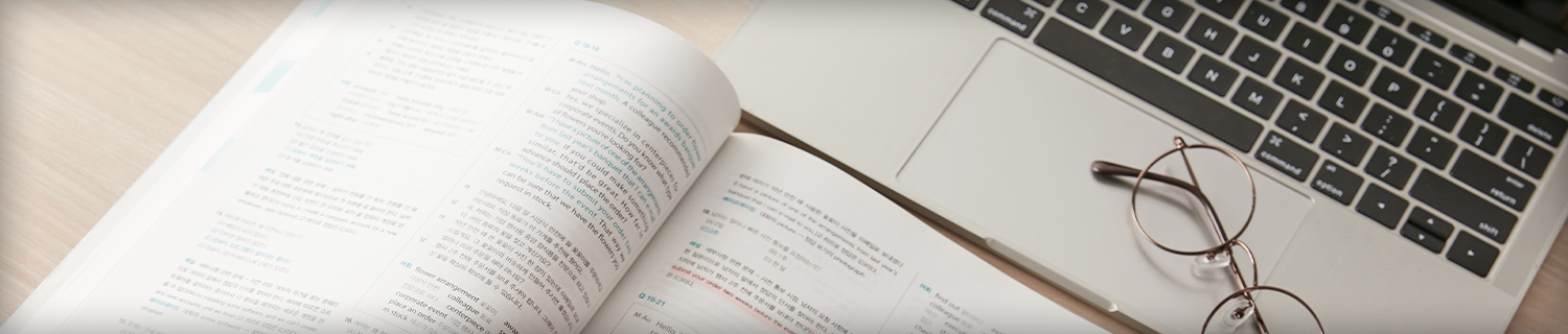 노트북과 책이 펼쳐져있고 그 위에 안경이 있는 사진